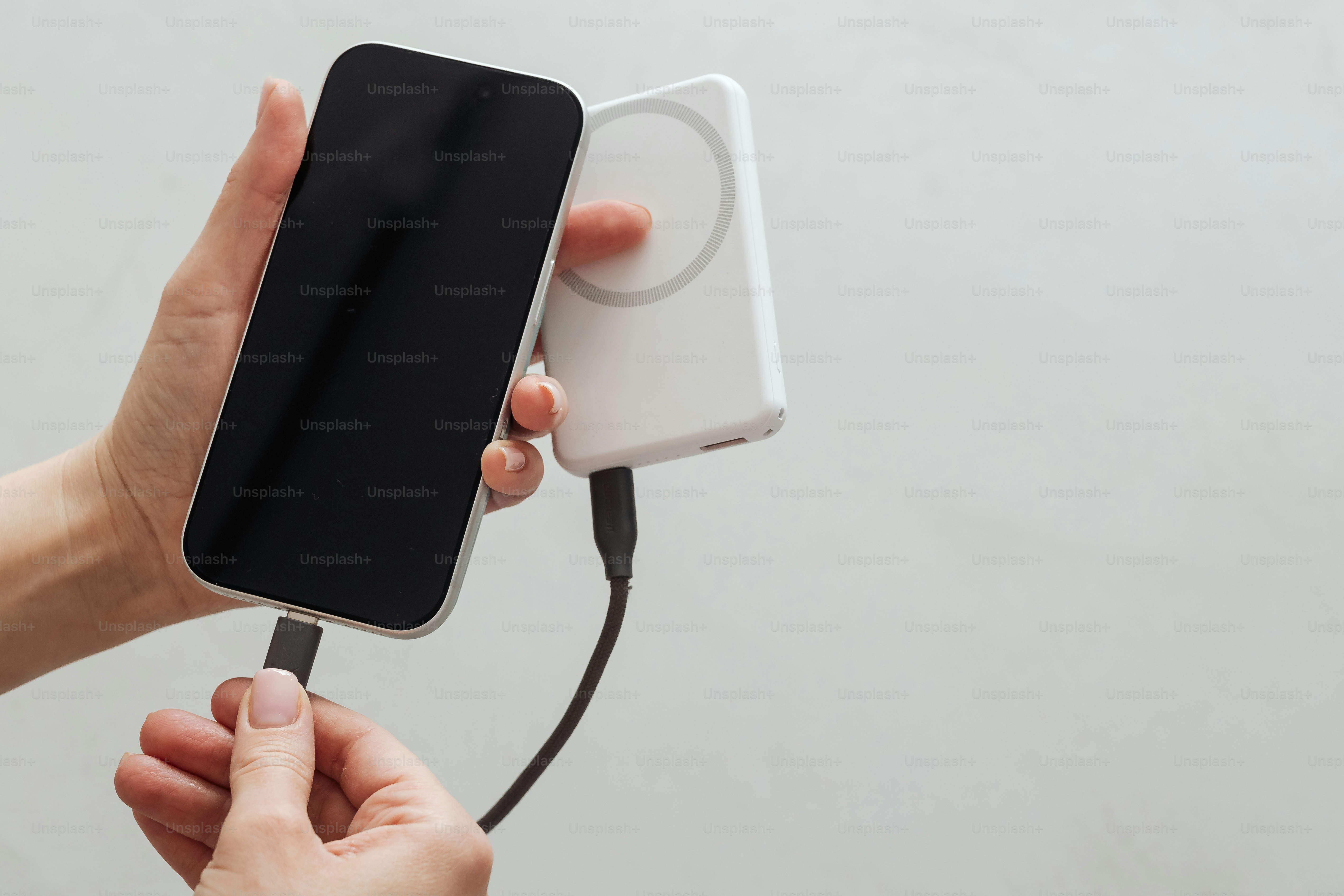 Hand plugging charging cable into smartphone and from power bank.